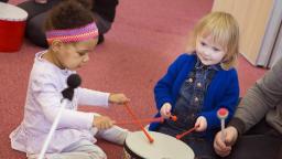 two young children banging a drum