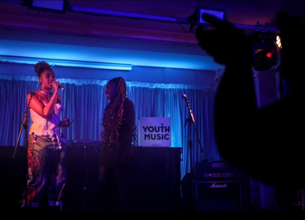 a woman stands on stage with ambient blue lighting behind