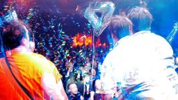 Two male musicians performing to a crowd. The image is slightly distorted effect, to make it look like double vision.