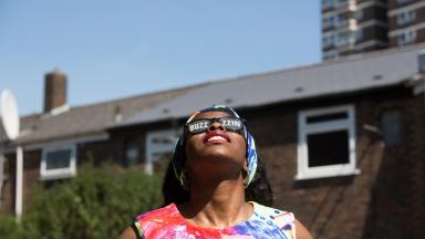 woman looking up at the sky wearing sunglasses that say buzzing