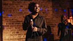 a young black woman smiles and holds a microphone