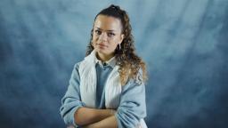 eva crosses her arms and poses against a blue background