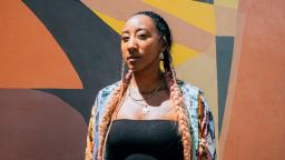 Woman with long plaits in front of mural