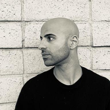 black and white photo of man in black tshirt against brick wall