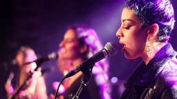 young musician singing into microphone with purple lighting