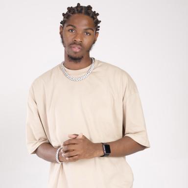 okeam wears a cream t shirt and poses against a white background