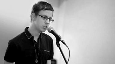 Black and white photo of Reece singing into a microphone