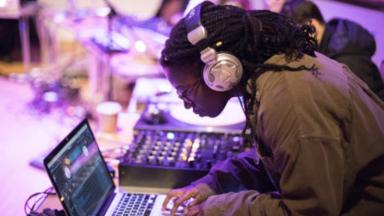 girl with headphones in producing music on a laptop