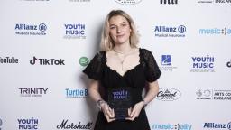 eva davies wears a black dress and holds her award 