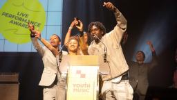 the spit game cheer on stage at the youth music awards 2022 as they receive the live performance award prize.