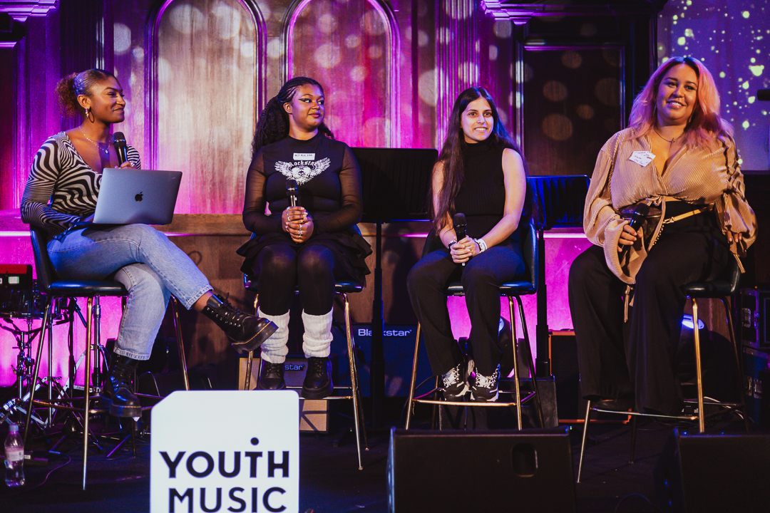 a group of women sit on stage as part of a panel