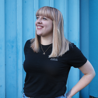 a woman with fair hair and a fringe smiles