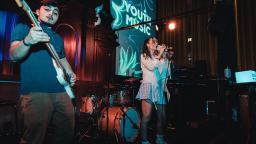 a band performs on stage with the youth music logo on scree