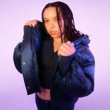 a woman with braids wears a dark puffer jacket 