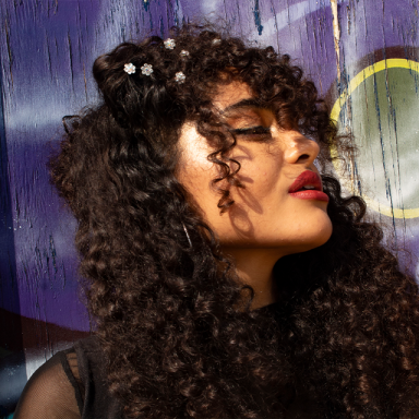 a woman with curly hair and red lipstick is shown in profile