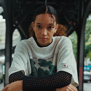 a woman wears a white t-shirt with black sleeves and looks at the camera