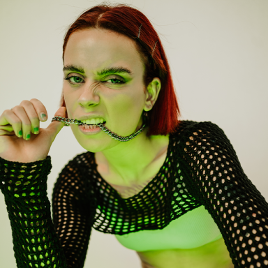 a woman with a red bob haircut bites her necklace