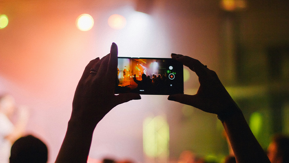 hands holding a phone to record a gig