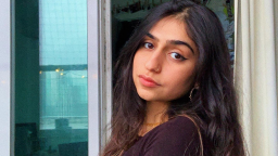 a young indian woman turns her head to face the camera. her hair is long, dark and wavy