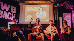 a group of young people sit on chairs and hold microphones. they are participating in a panel.