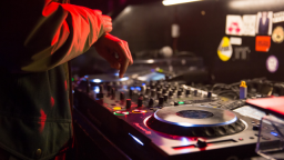 Image of a person DJ-ing. The image is a close up of their hand and the production equipment.